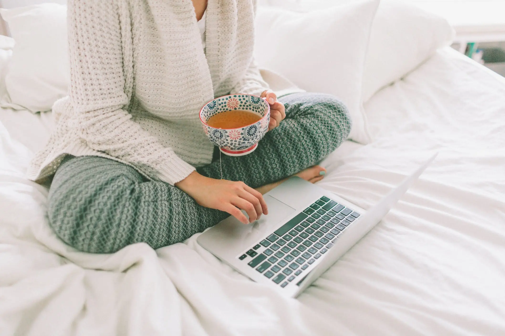 A person sitting on the bed with a laptop