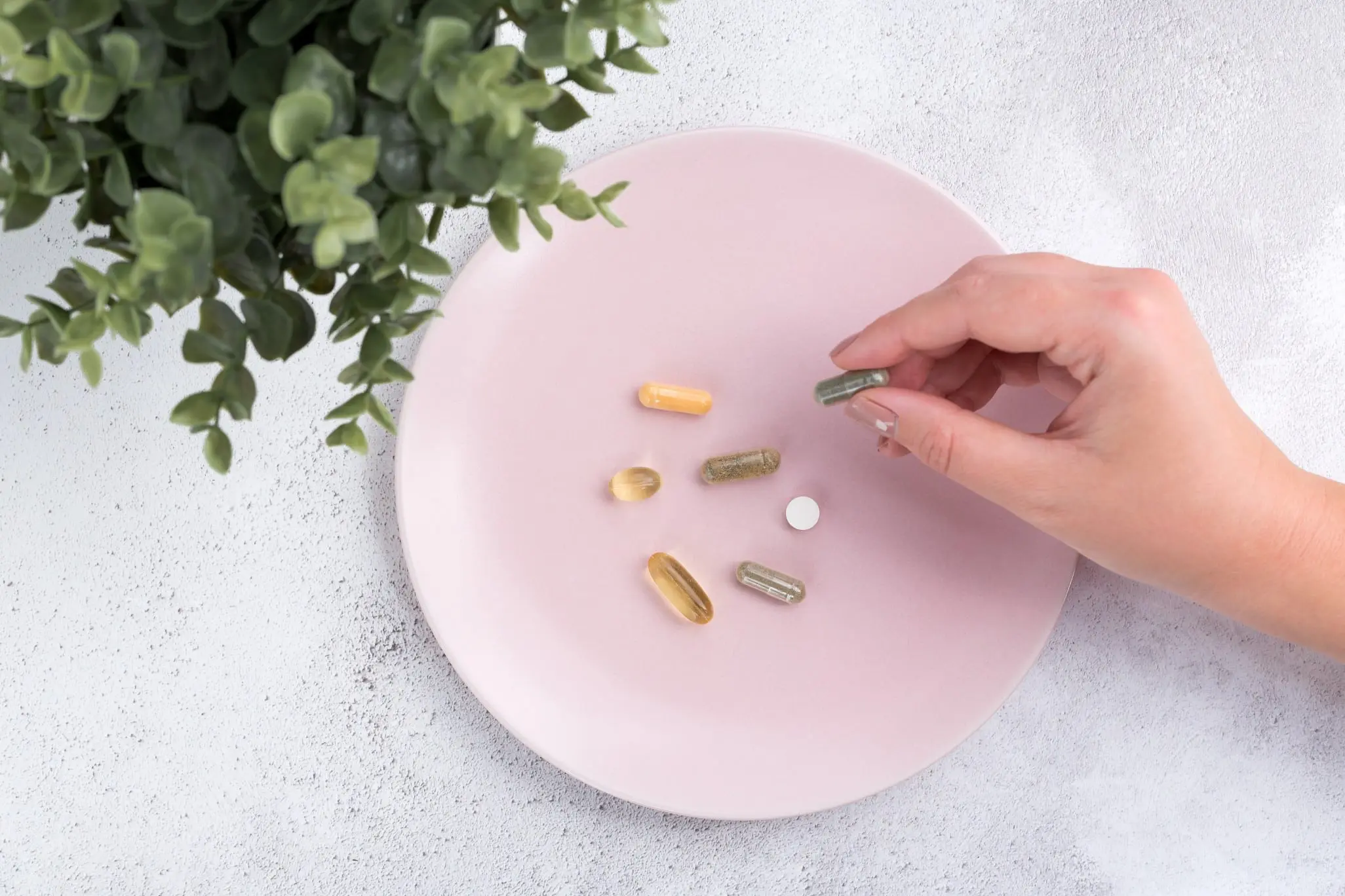 A person is holding onto some pills on the plate