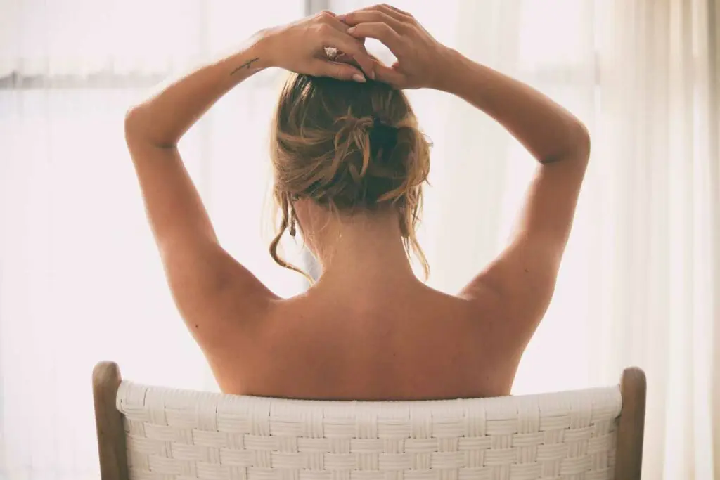 A woman sitting in a chair with her hands behind her head.