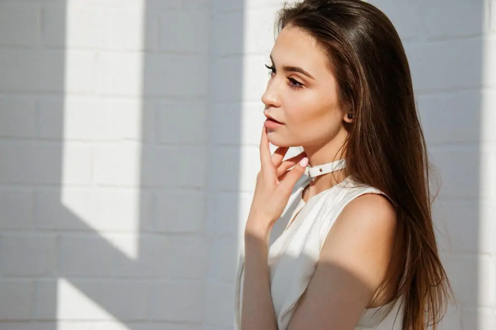 A woman with long hair wearing white is looking at the camera.
