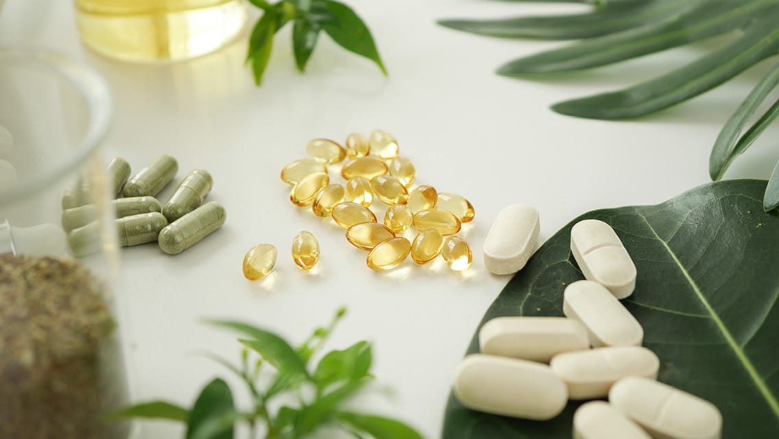 A table topped with lots of pills and green plants.