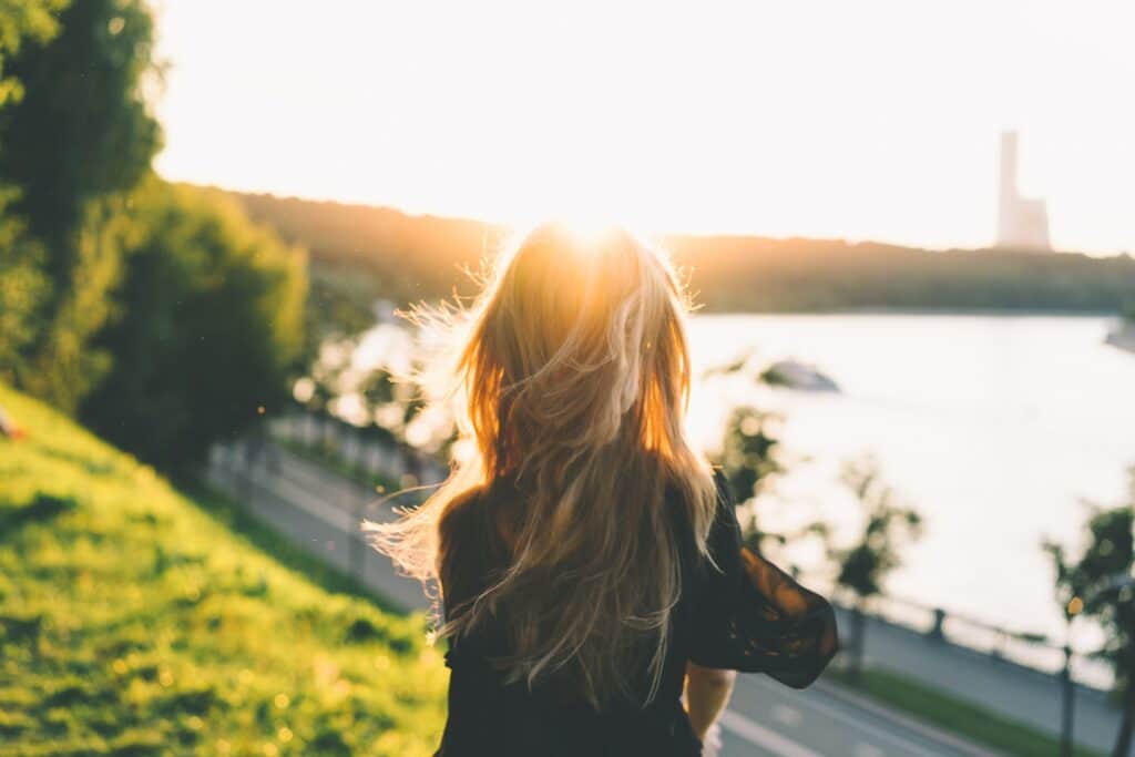 A woman standing on top of a hill near the water.