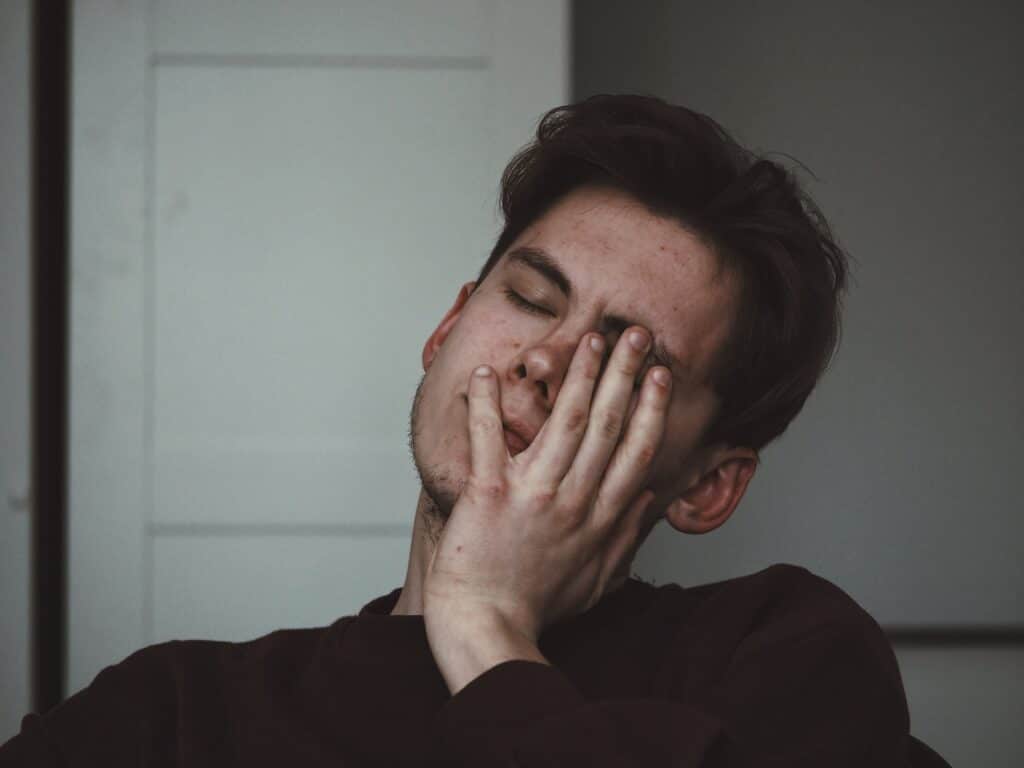 A man with his hand covering his face