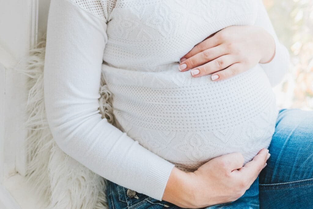 A woman holding her stomach in the middle of her belly.