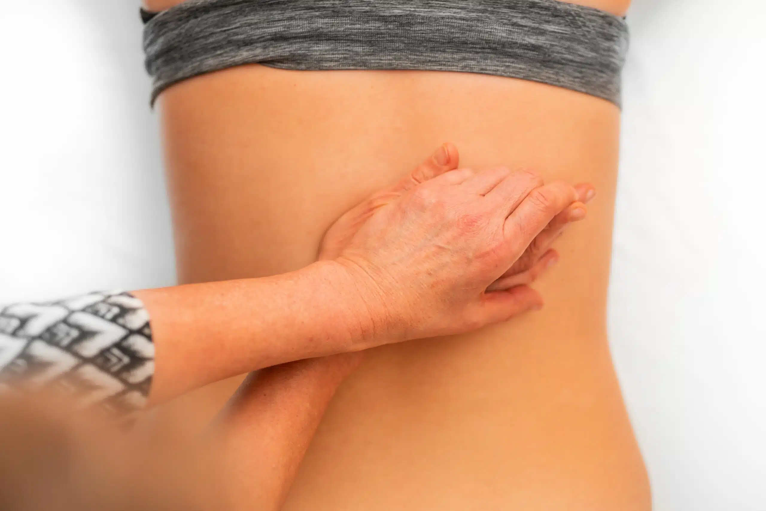 A person is holding their hands over the stomach of another person.