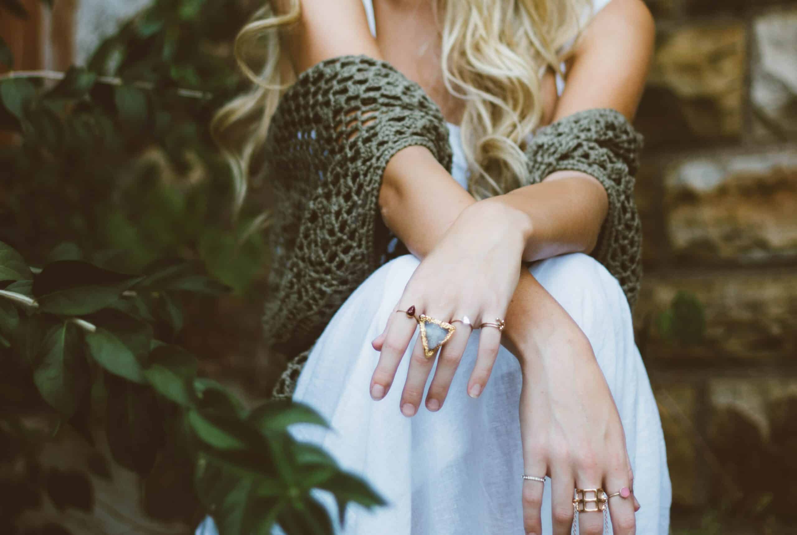 A woman sitting on the ground with her hands in front of her.