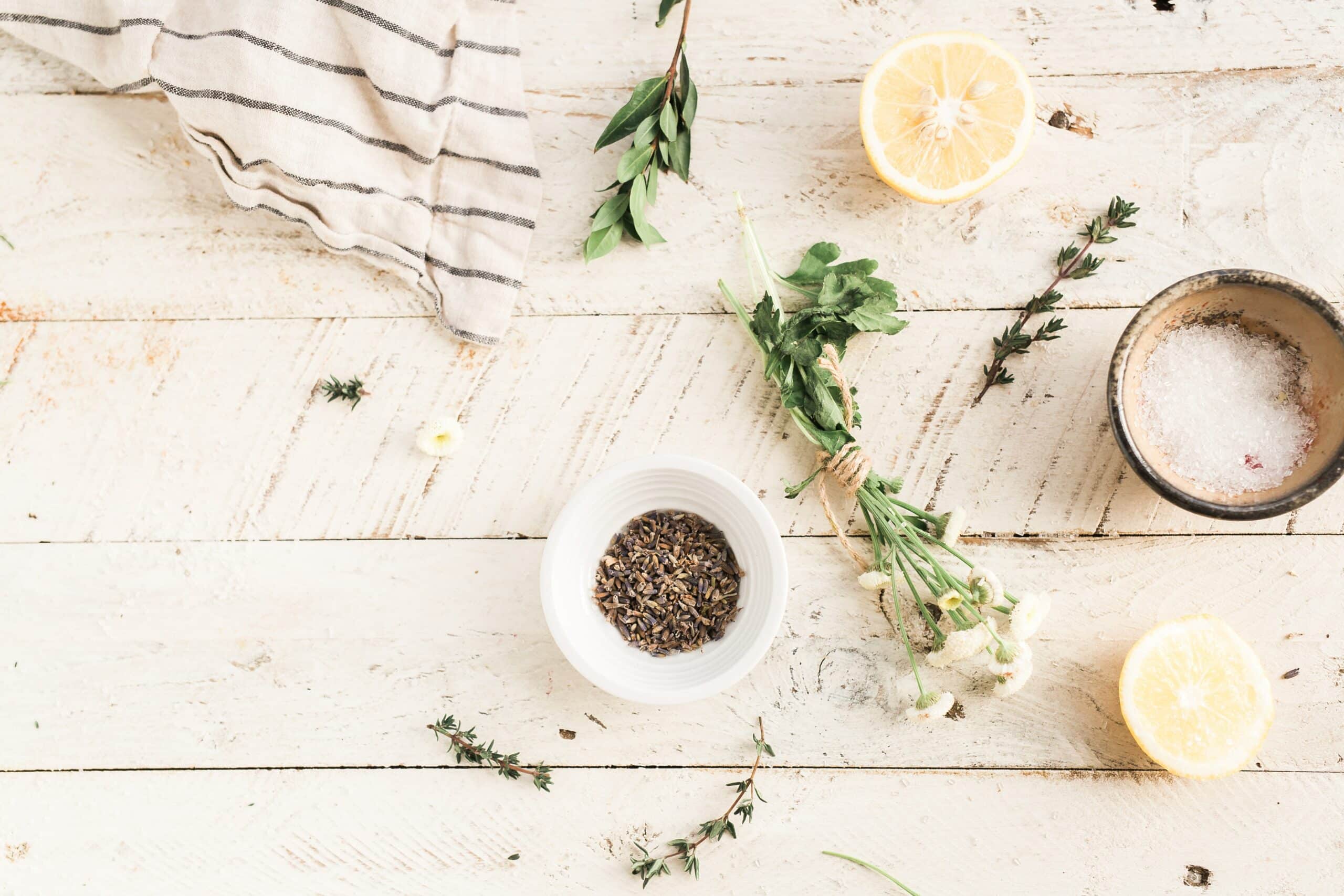 A bowl of herbs and a lemon on top of the table.