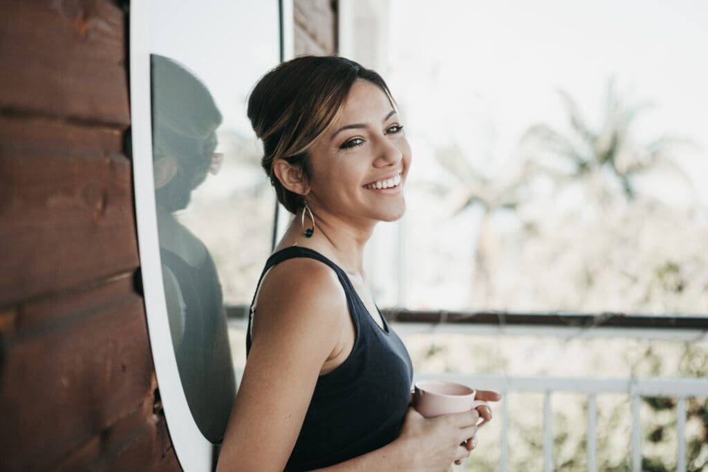 A woman smiling while holding onto a surfboard.