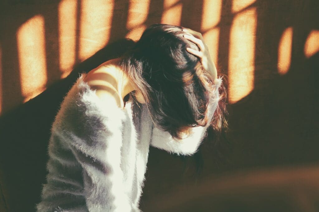 A woman in white jacket holding her head.