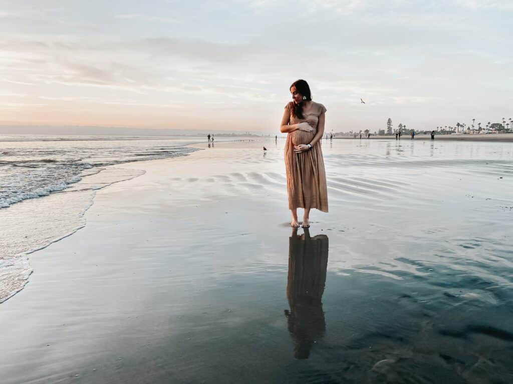 A woman standing on the beach in front of water.