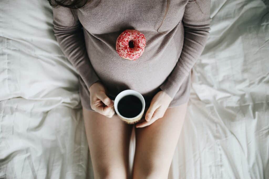 A pregnant woman holding a cup of coffee.