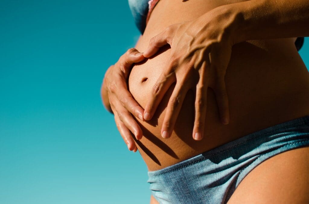 A woman in blue bikini holding her stomach.