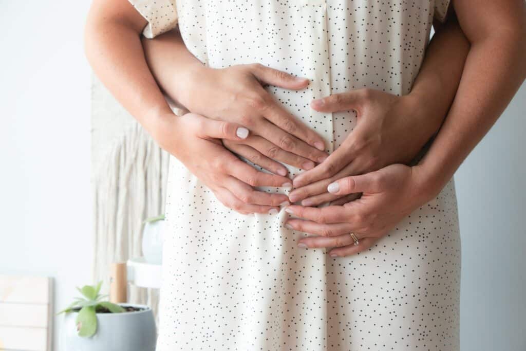 A woman holding her stomach with two hands.