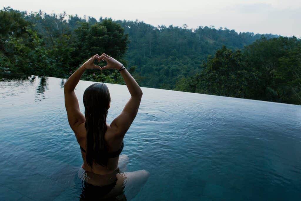 A woman in the water with her arms up.