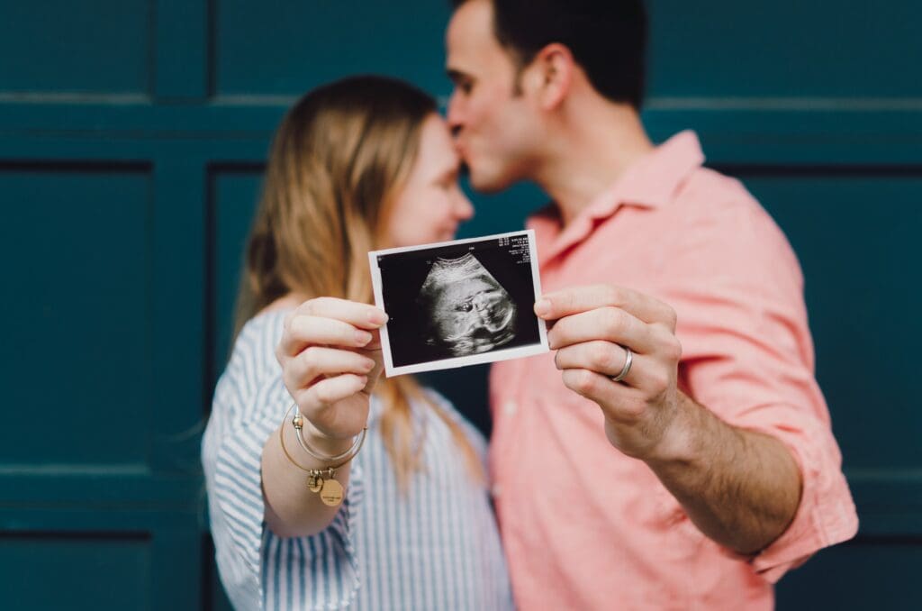 A man and woman holding up a picture of their baby.