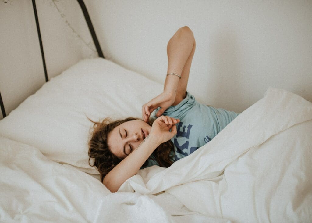 A woman laying in bed with her head on the pillow.