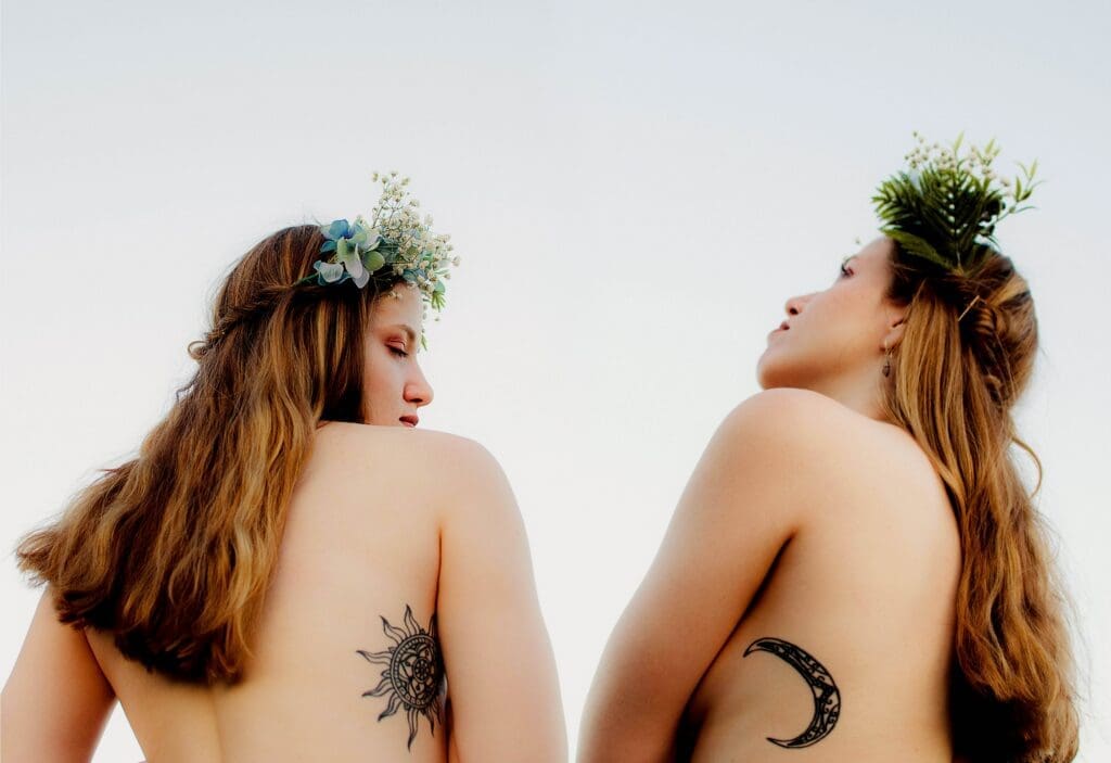 Two women with tattoos and one has a flower in her hair.