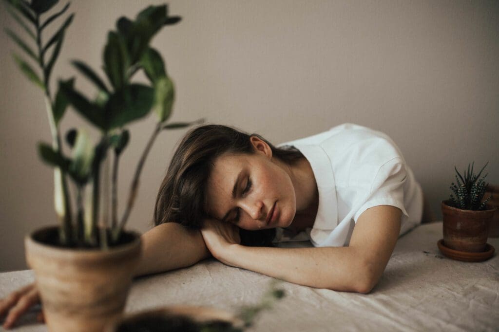 A woman is sleeping on the bed with her head resting on her arms.