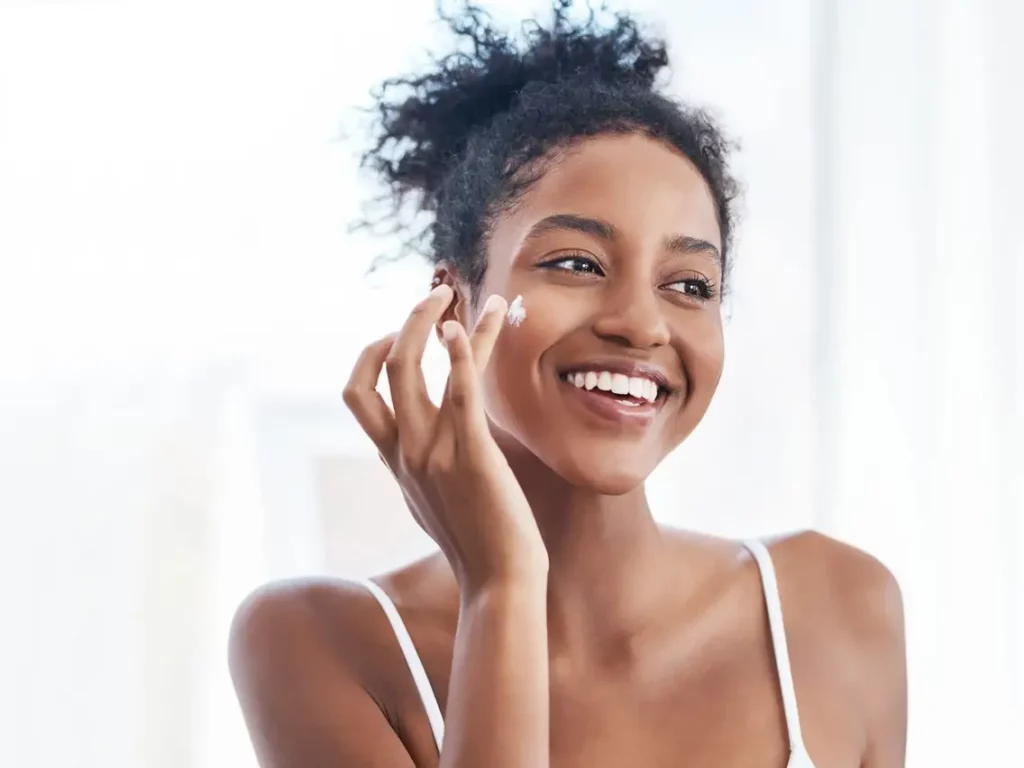 A woman is smiling while putting on makeup.