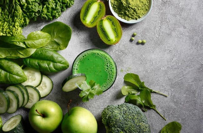 A table topped with green vegetables and fruits.