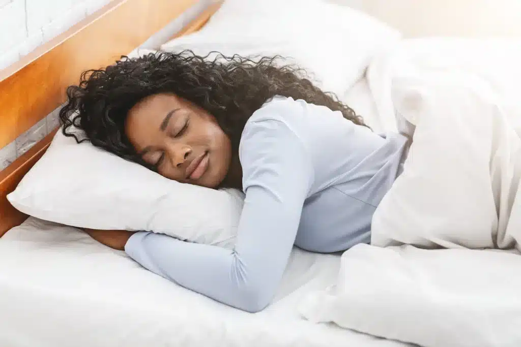 A woman sleeping in bed with her head on the pillow.