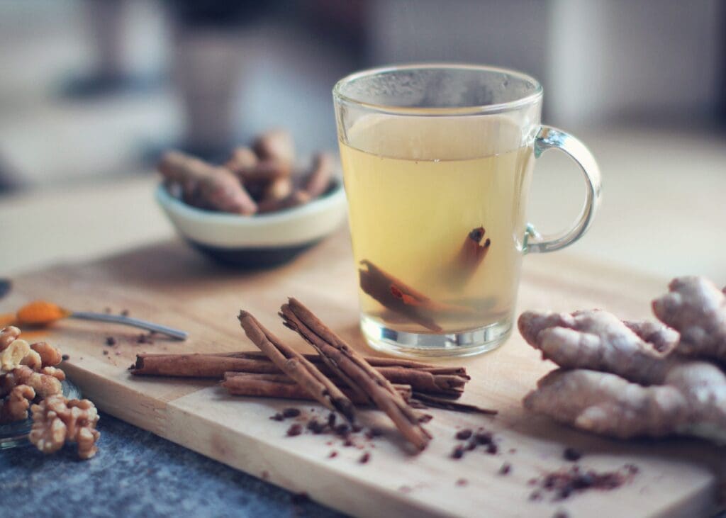 A cup of tea and some cinnamon sticks on a table.