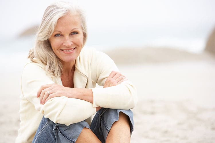 A woman sitting on the beach with her arms crossed.