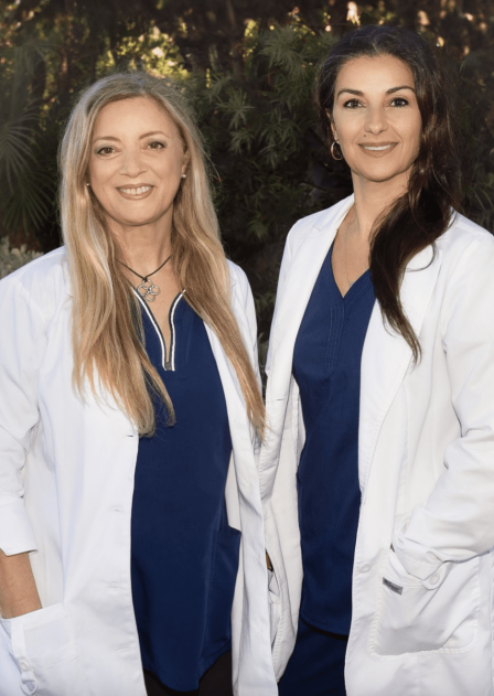 Two women in white lab coats standing next to each other.