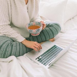 Laptop keyboard and tea on white bedding